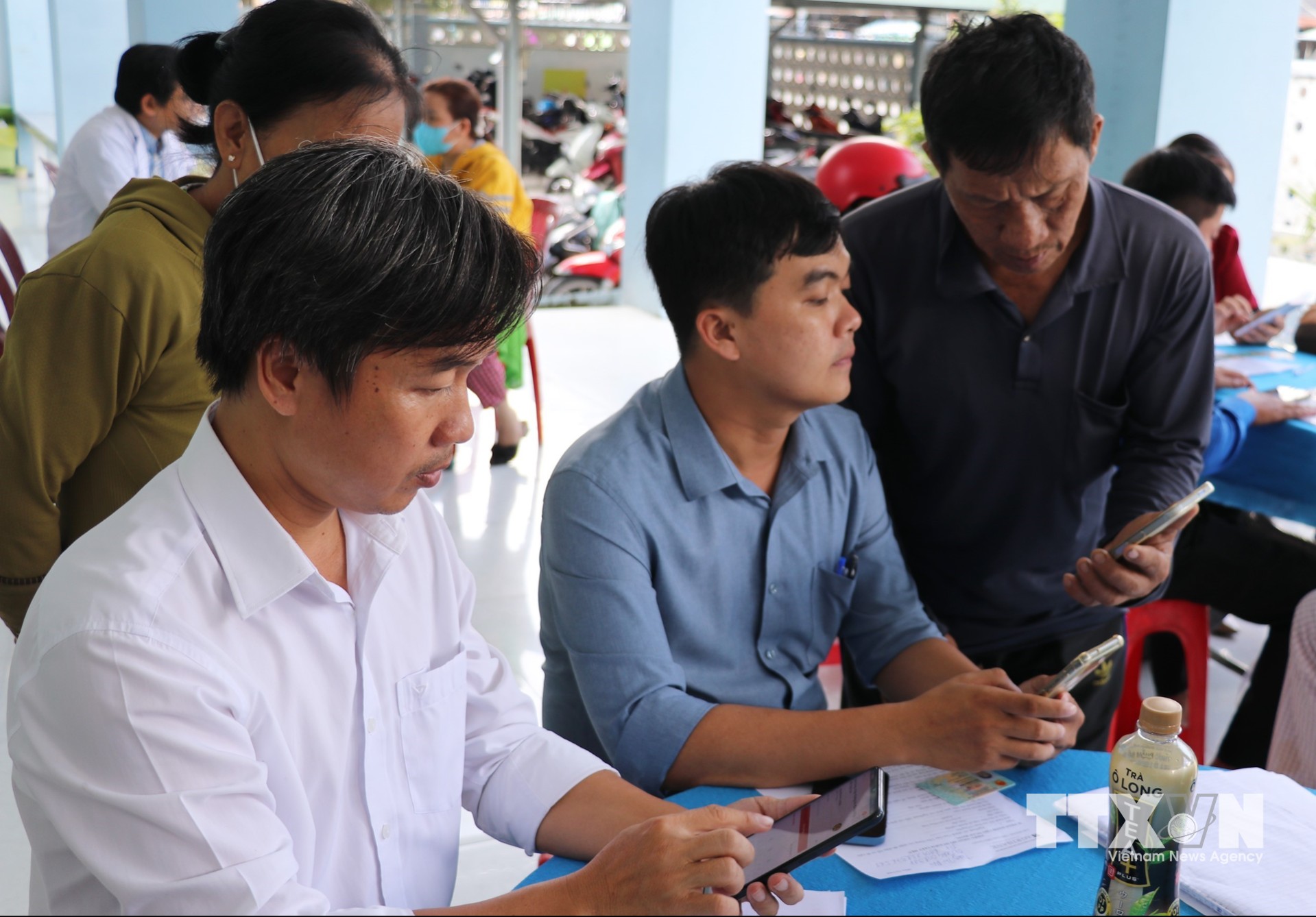 Người dân được nhân viên y tế và cán bộ ấp hỗ trợ làm thủ tục khai báo thông tin sức khỏe. (Ảnh: Hữu Chí/TTXVN)